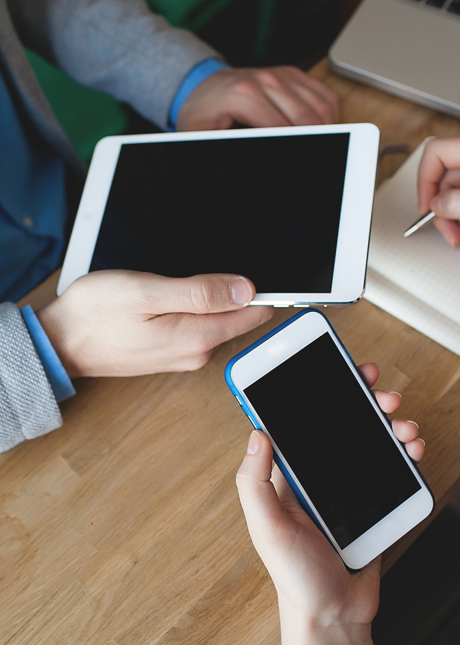 Smartphone, tablet and laptop with notepad in hands of man and w